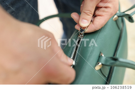 Male hands zip up green leather bag closeup 106238519