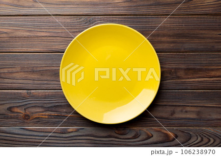 Top view of empty yellow plate on wooden background. Empty space for your design 106238970