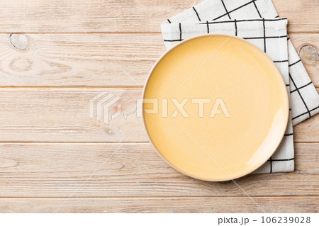 Top view on colored background empty round yellow plate on tablecloth for food. Empty dish on napkin with space for your design Top view on colored background empty round yellow plate on tablecloth for food. Empty dish on napkin with space for your design 106239028