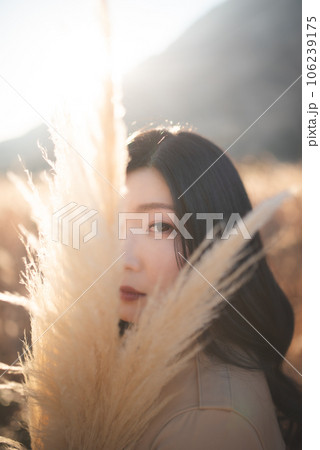 パンパスグラス越しにこちらを見る女性 106239175