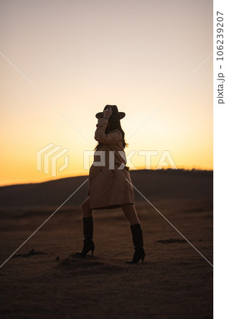 夕焼けの草千里でポーズをとるトレンチコートの女性 夕焼けの草千里でポーズをとるトレンチコートの女性 106239207