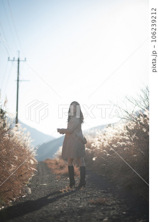 すすき草原の間のじゃり道を振り向きながら歩く女性の後ろ姿 すすき草原の間のじゃり道を振り向きながら歩く女性の後ろ姿 106239212