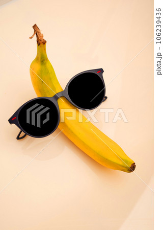A funny banana with black sunglasses on a white background. 106239436