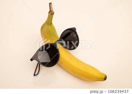 A funny banana with black sunglasses on a white background. 106239437
