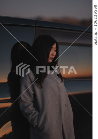 夕焼けに染まる車の寄りかかる女性 夕焼けに染まる車の寄りかかる女性 106239599