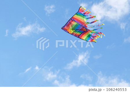 Kite in a blue sky. Rainbow Delta Kite flying among the clouds. Happy growing years moment. Outdoor time spending. Aspirations, target, inspiration concept. Freedom and summer holiday. Childhood dream 106240553