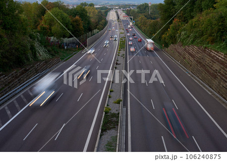 Night lights from car headlights on roundabout in night city. Traces of headlights on the road at night, long exposure. Drone aerial shot. Panoramic aerial view of illuminated road overpass and road 106240875