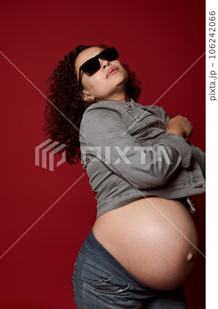 Multi-ethnic pregnant woman isolated over red studio background. Childbearing. Pregnancy. Maternity fashion. Lifestyle Multi-ethnic pregnant woman isolated over red studio background. Childbearing. Pregnancy. Maternity fashion. Lifestyle 106242066