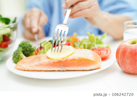 Asian elderly woman patient eating salmon stake and vegetable salad for healthy food in hospital. Asian elderly woman patient eating salmon stake and vegetable salad for healthy food in hospital. 106242720