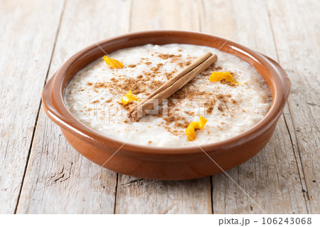 Arroz con leche. Rice pudding with cinnamon in clay bowl on wooden table Arroz con leche. Rice pudding with cinnamon in clay bowl on wooden table 106243068
