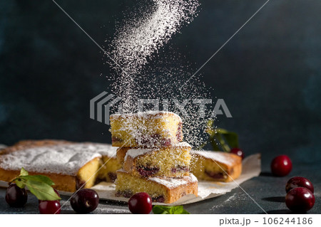 Powdered sugar decorates sponge cake with a cherry Powdered sugar decorates sponge cake with a cherry 106244186