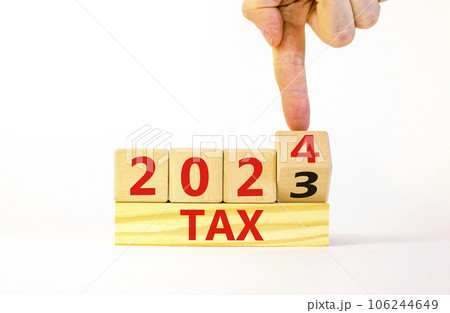 2024 tax new year symbol. Businessman turns a wooden cube and changes words Tax 2023 to Tax 2024. Beautiful white table white background, copy space. Business 2024 tax new year concept. 106244649