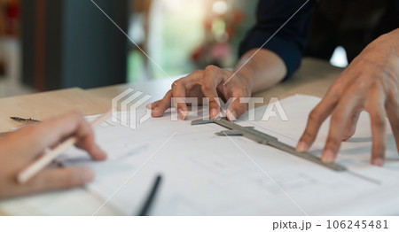 Closeup hand of engineer team with construction work plan discussion together blueprint on working table in construction site with safety helmet 106245481