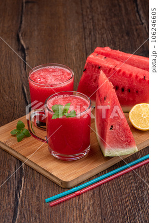 Watermelon squeezed juice, watermelon pieces and lemon on a wooden background. 106246605