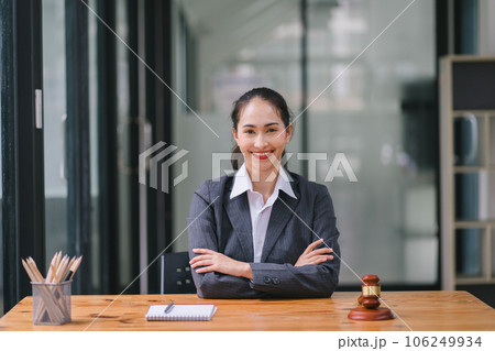 A businesswoman and lawyers are discussing contract papers with a brass scale on a desk in an office. The concepts of law, legal services, advice, justice, and real estate are being discussed. 106249934