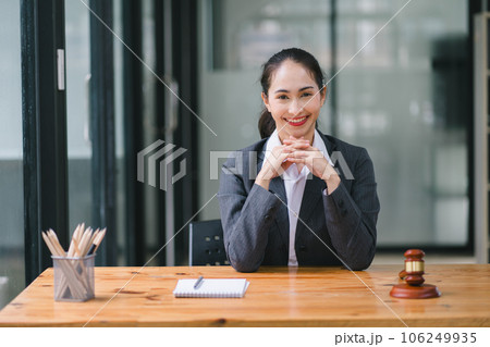 A businesswoman and lawyers are discussing contract papers with a brass scale on a desk in an office. The concepts of law, legal services, advice, justice, and real estate are being discussed. A businesswoman and lawyers are discussing contract papers with a brass scale on a desk in an office. The concepts of law, legal services, advice, justice, and real estate are being discussed. 106249935
