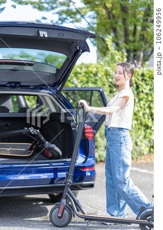 旅行先の駐車場で電動キックボードを車のトランクに収納する若くて可愛い女性 旅行先の駐車場で電動キックボードを車のトランクに収納する若くて可愛い女性 106249956
