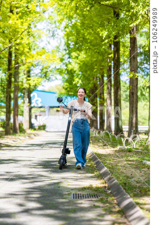 緑が美しい並木道を電動キックボードで爽快に走る若くてかわいい女性|電動キックボードイメージ 緑が美しい並木道を電動キックボードで爽快に走る若くてかわいい女性|電動キックボードイメージ 106249989