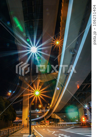 高速道路の下を走る車の光跡 106251404