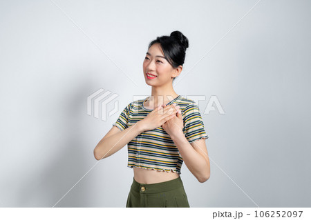 Portrait of touched young woman feeling flattered, holding hands on heart and smiling, say thank you 106252097