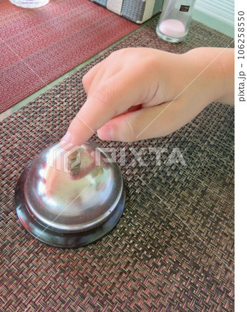 喫茶店のテーブルに置かれている呼び鈴を鳴らす手 喫茶店のテーブルに置かれている呼び鈴を鳴らす手 106258550