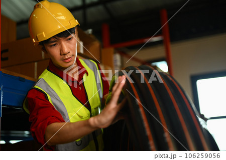 Man worker wearing hard hat carrying plastic tube in warehouse. Logistics, and manufacture storehouse occupation Man worker wearing hard hat carrying plastic tube in warehouse. Logistics, and manufacture storehouse occupation 106259056