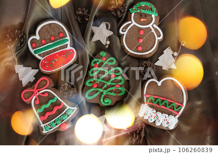 Banner for Christmas and New Year gingerbread. Christmas trees, toys, snowmen, garlands on a background of brown silk fabric. Bright bokeh. 106260839