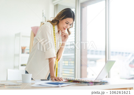 Southeast asian woman designer busy using laptop computer in fashion design studio 106261621