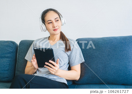 Young adult asian woman wear headphone listen music and relax using digital tablet Young adult asian woman wear headphone listen music and relax using digital tablet 106261727