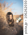 すすきの中しゃがんで下に目線を落とす黒髪の女性 106262030