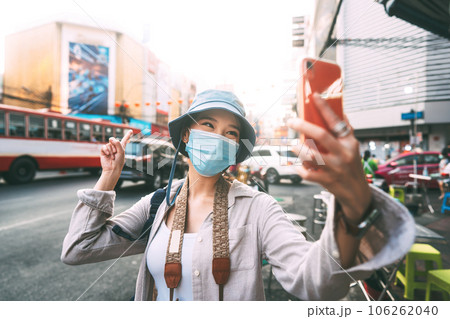Young adult asian woman traveller wear face mask for covid-19 traveling in local city on summer day Young adult asian woman traveller wear face mask for covid-19 traveling in local city on summer day 106262040
