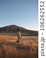 阿蘇の草千里でトレンチコートを着た女性がこちらを見て立っている 106262552