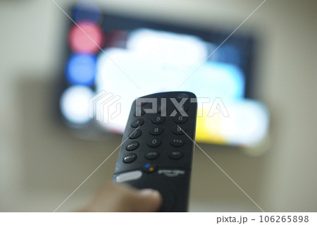 Hand with TV remote control, switching TV series from streaming service platform. The new way of enjoying entertainment at home. Hand with TV remote control, switching TV series from streaming service platform. The new way of enjoying entertainment at home. 106265898