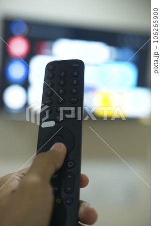 Hand with TV remote control, switching TV series from streaming service platform. The new way of enjoying entertainment at home. 106265900