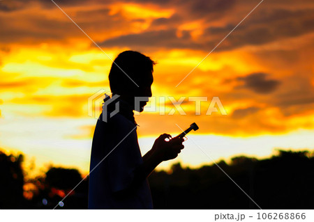 Silhouette of a boys piloting a drone on A Rural Setting on sunset 106268866