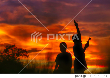 Silhouette of a boys piloting a drone on A Rural Setting on sunset 106268874