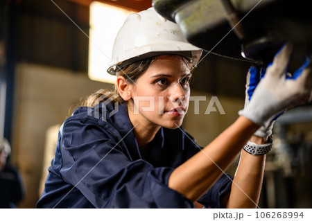 Portrait of female mechanical engineer repairing engine machine at garage Portrait of female mechanical engineer repairing engine machine at garage 106268994