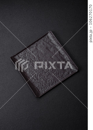 Empty black square ceramic plate on dark concrete background 106270170