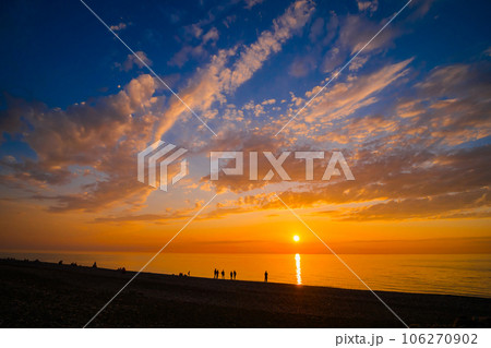 People are looking at dramatic sunset over the sea surface in the evening People are looking at dramatic sunset over the sea surface in the evening 106270902