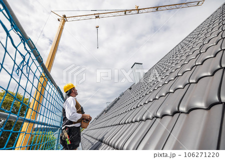 roofer on construction site operating crane 106271220