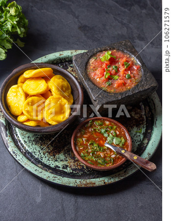 Sopaipilla. Latin American food. Traditional chilean homemade pumpkin sopaipillas with typical salsas - chancho en piedra tomato sauce in stone mortar and spicy pebre Sopaipilla. Latin American food. Traditional chilean homemade pumpkin sopaipillas with typical salsas - chancho en piedra tomato sauce in stone mortar and spicy pebre 106271579