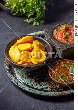 Sopaipilla. Latin American food. Traditional chilean homemade pumpkin sopaipillas with typical salsas - chancho en piedra tomato sauce in stone mortar and spicy pebre Sopaipilla. Latin American food. Traditional chilean homemade pumpkin sopaipillas with typical salsas - chancho en piedra tomato sauce in stone mortar and spicy pebre 106271581