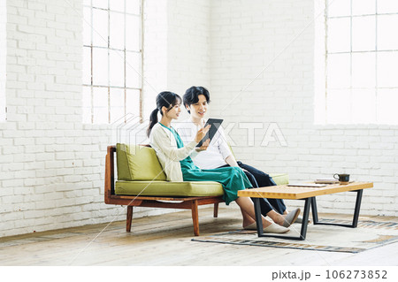 リビングのソファーでタブレットを見る男女カップル 106273852
