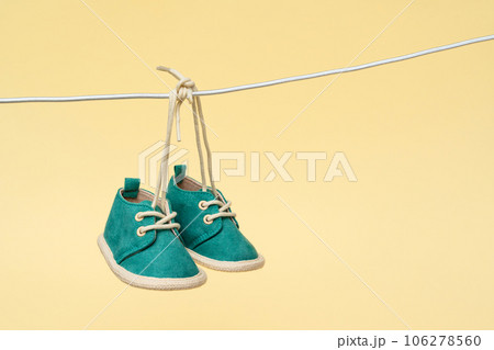 Newborn concept comes alive with tiny baby shoes swaying on a clothesline Newborn concept comes alive with tiny baby shoes swaying on a clothesline 106278560
