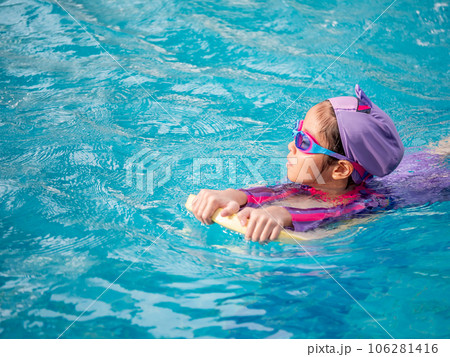 Asian child or kid girl wearing swimming suit to learning on swimming pool , learn and training swim on kick board Asian child or kid girl wearing swimming suit to learning on swimming pool , learn and training swim on kick board 106281416