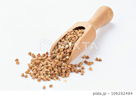 Wooden scoop of roasted buckwheat on a white background. Wooden scoop of roasted buckwheat on a white background. 106282484