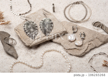Beautiful Silver and Pearl Jewelry on white stones and sand. Various jewelry - bracelets, necklaces and rings. 106283268