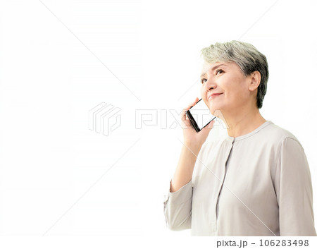 Listening to clients requirements. Beautiful senior woman talking on smart phone and smiling while standing against white background. 106283498