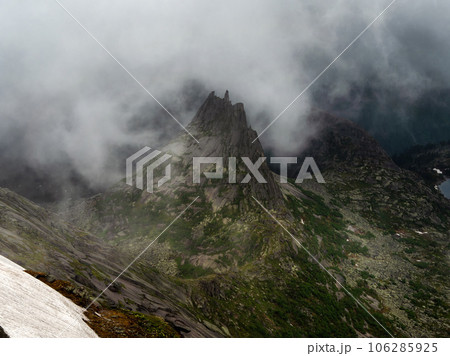 Impressive pointed peak with jagged edges in dense frightening thunderclouds, bad weather in the mountains, difficult trekking. Lost world in the mountains. 106285925