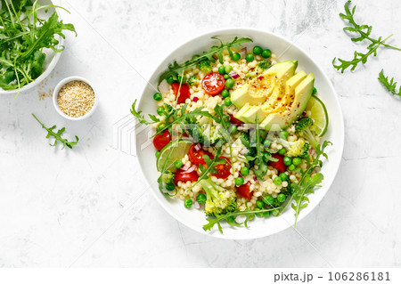 Couscous salad with broccoli, green peas, tomatoes, avocado and fresh arugula. Healthy natural plant based vegetarian food for lunch, israeli cuisine, top view 106286181